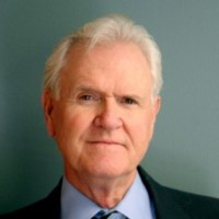 A man in suit and tie with white hair.