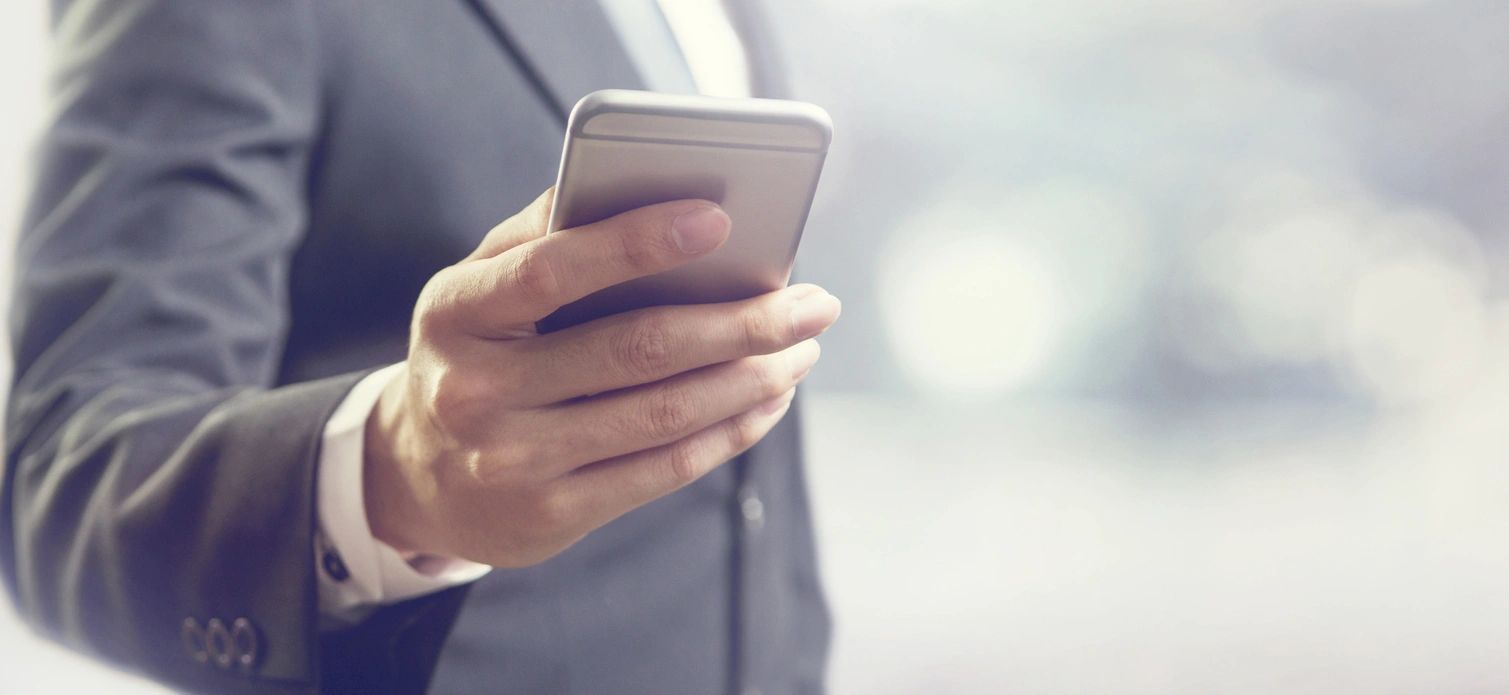 A man in suit holding his cell phone.