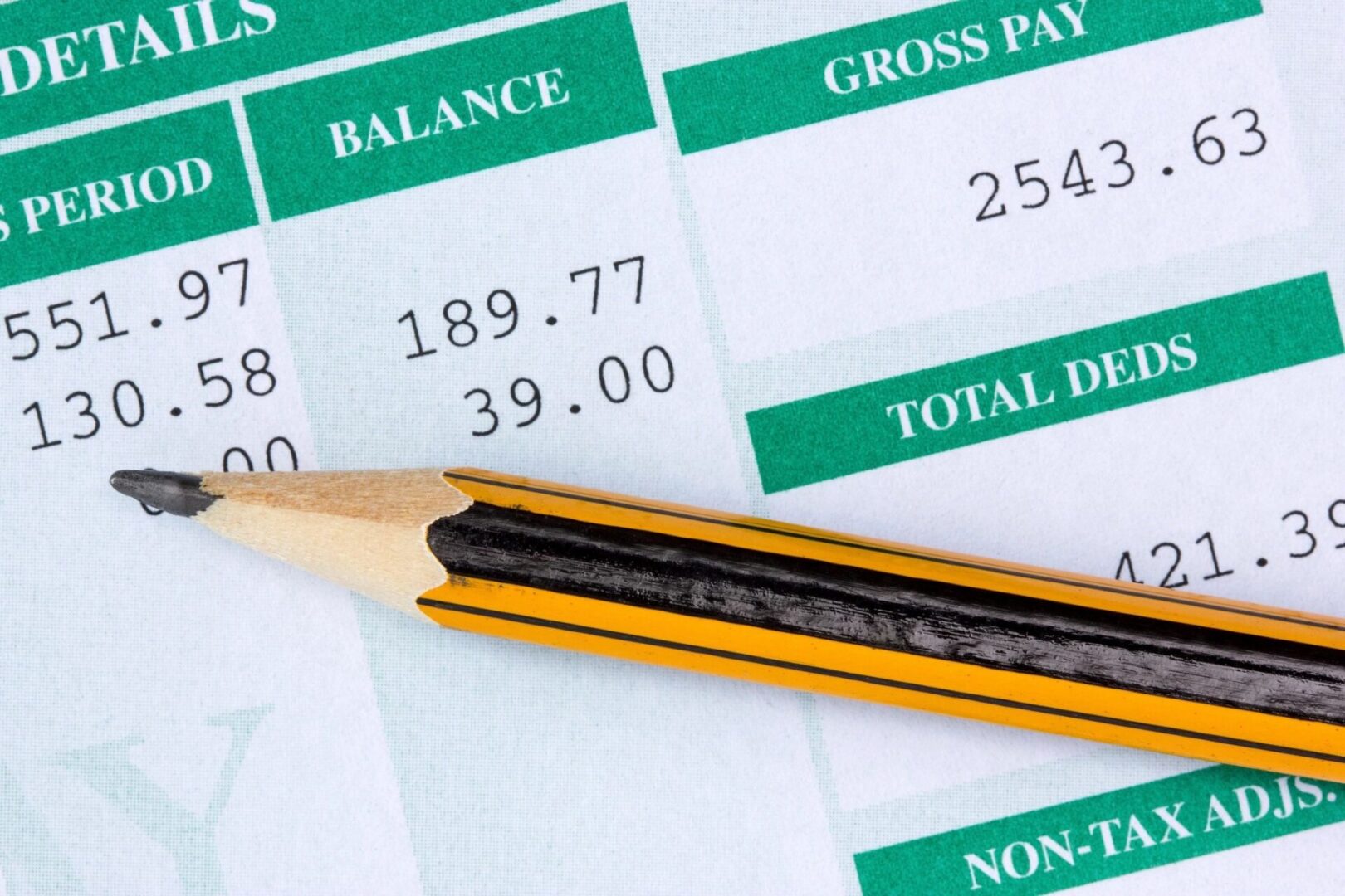 A pencil sitting on top of a paper with some bills.