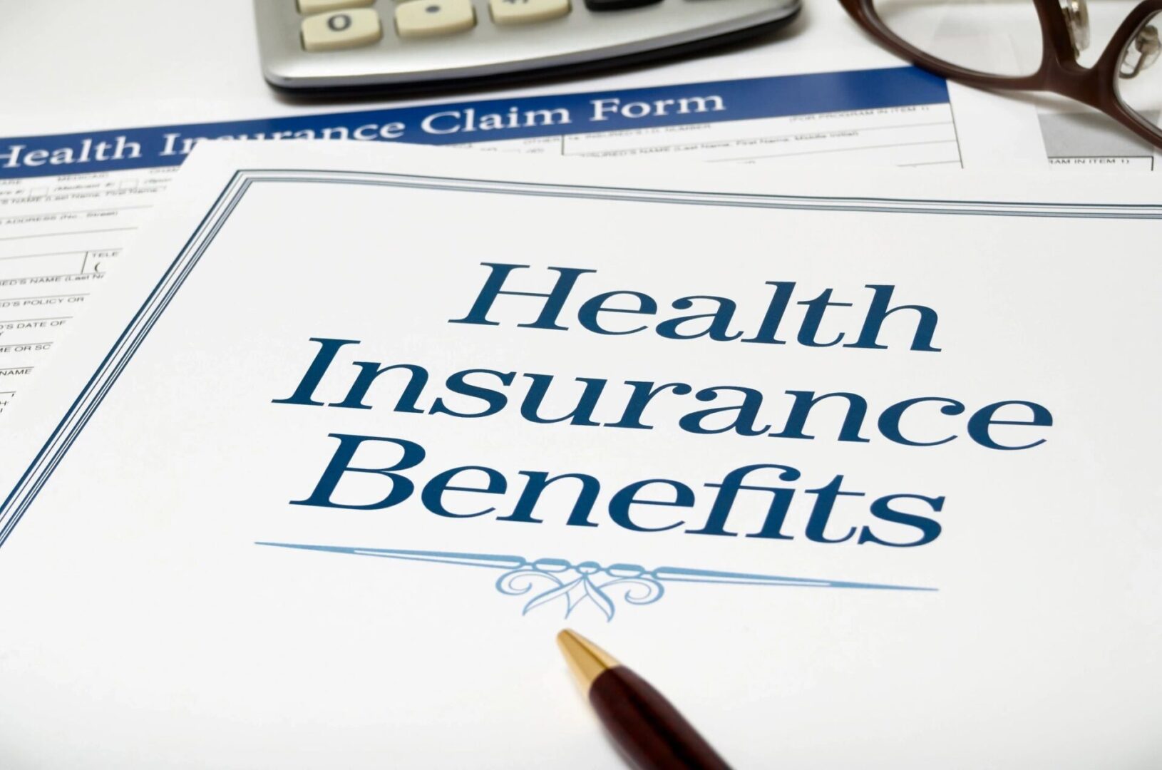 A health insurance benefits form with a pen and calculator.